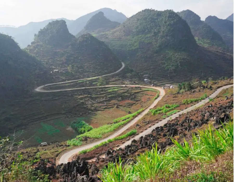 A winding mountain pass in Ha Giang surrounded by limestone peaks.