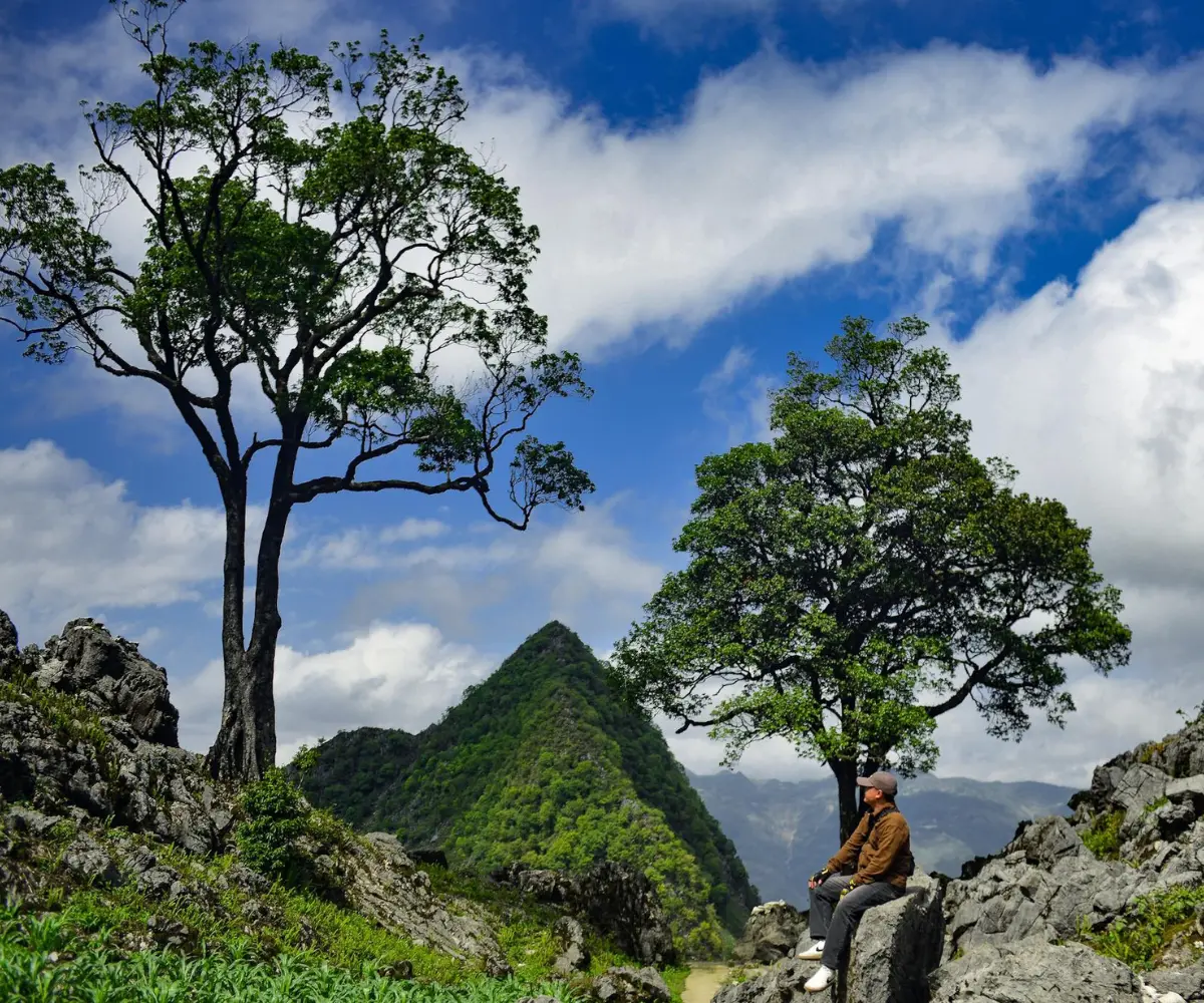 Scenic view of the Ha Giang Loop with winding mountain passes, majestic rocky peaks, and motorbikes on the road.