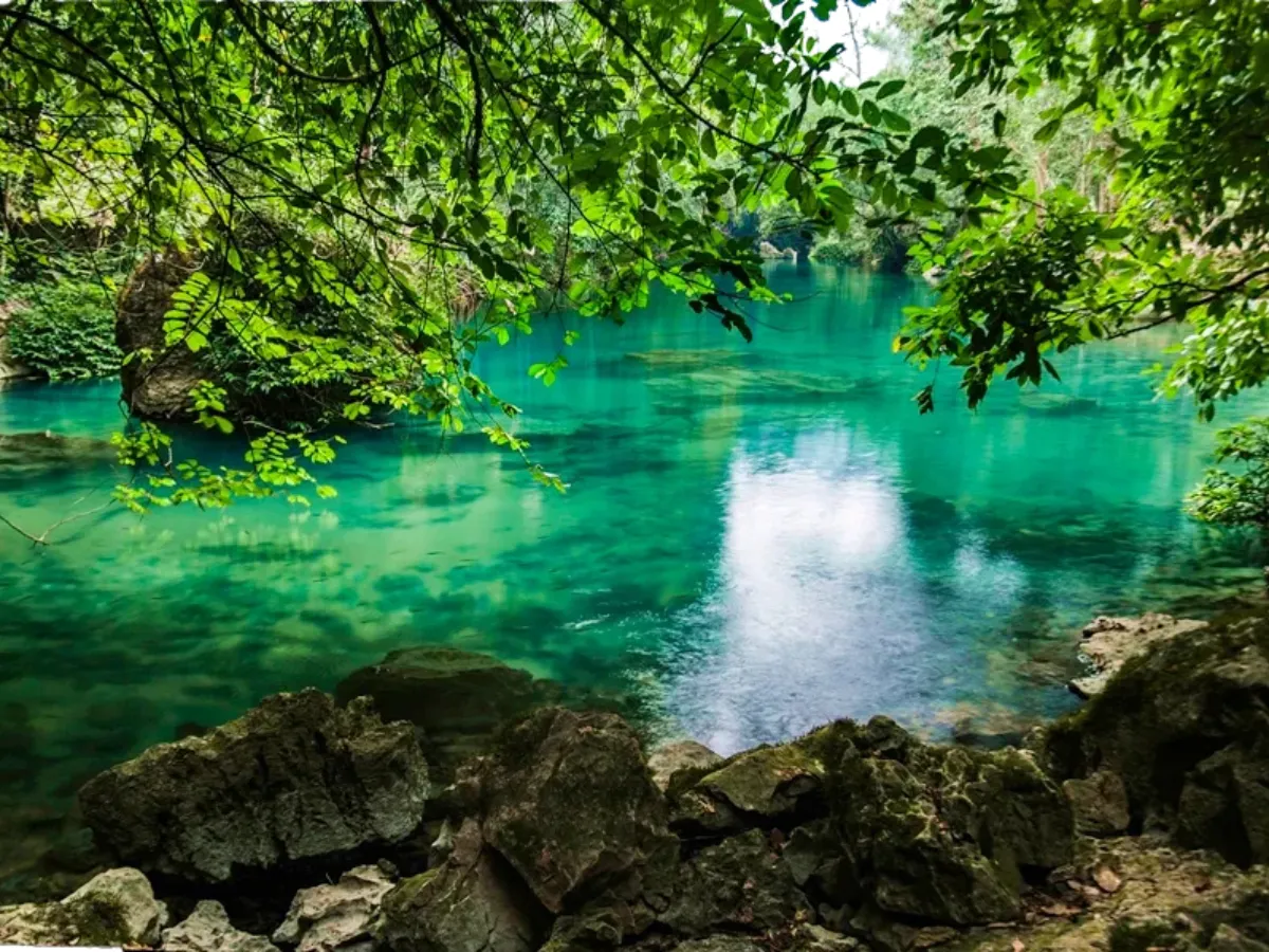 Clear blue waters of Suoi Lenin surrounded by green hills, part of the Cao Bang Loop vs Ha Giang Loop journey